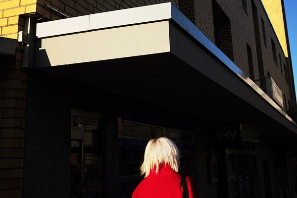 Color street photography by Manuel Armenis, woman in red jacket