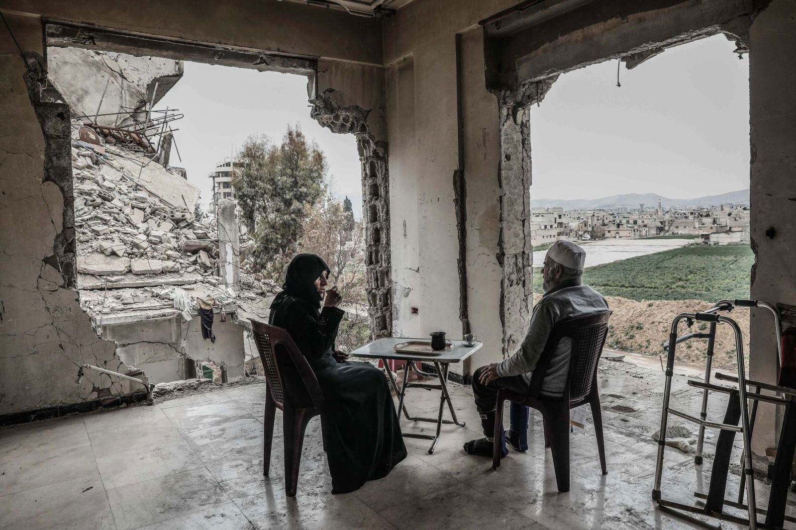 Syrian Umm Mohammed and her husband drink coffee at their destroyed home in the rebel-held town of Douma, on the outskirts of the capital Damascus. Color documentary photography by Sameer Al-Doumy