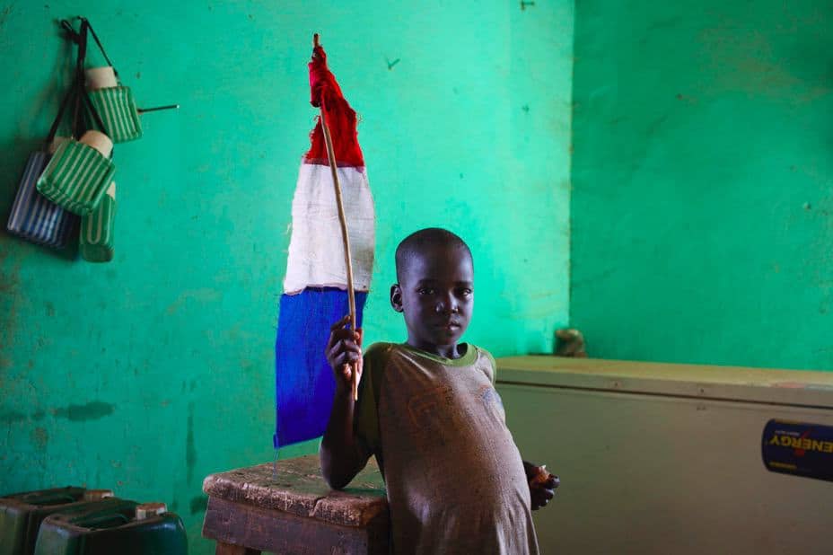 Photo of a boy in Mali holding a French Flag