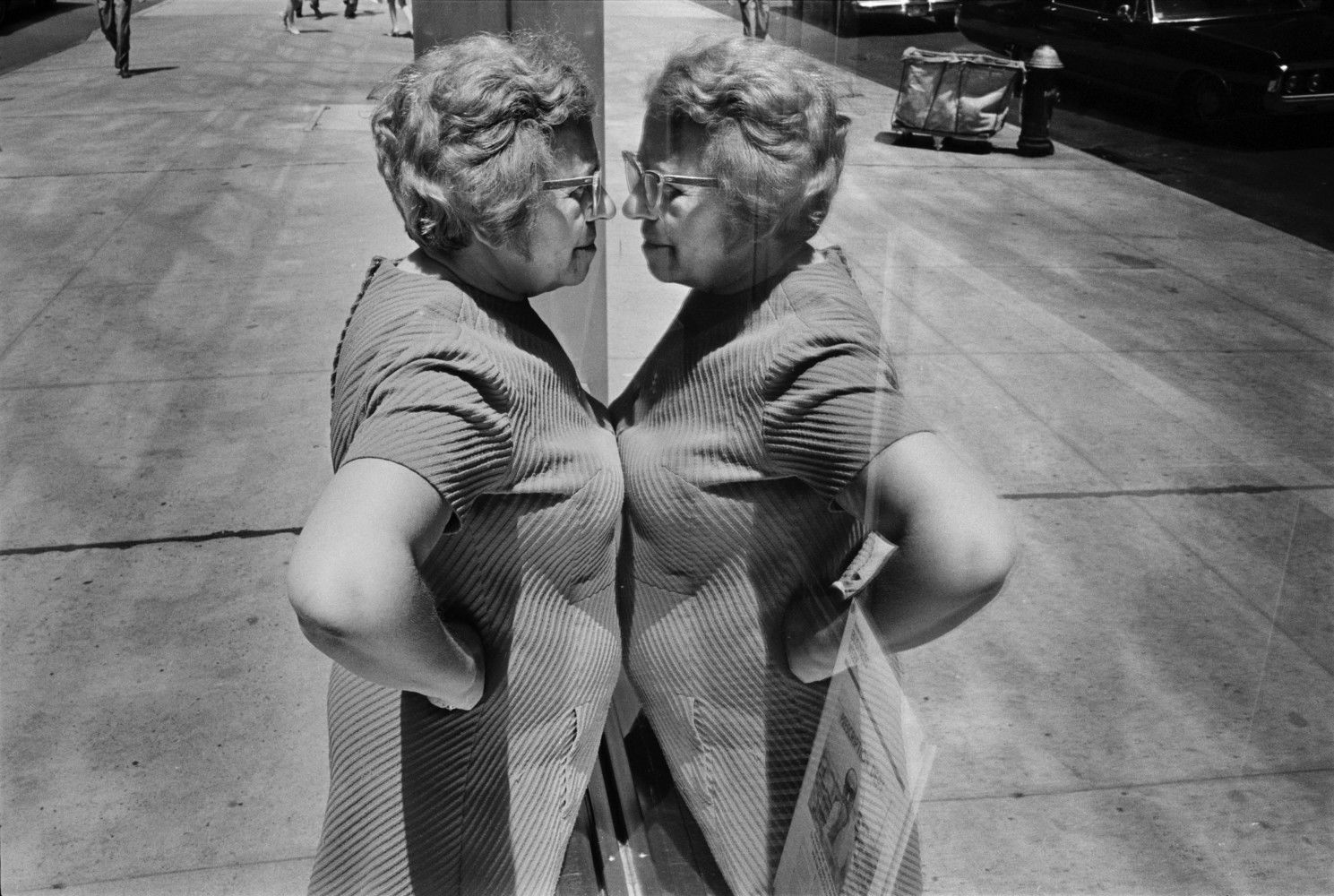 Black and white street photography by Richard Kalvar, a women looks at her reflection in a shop window in New York City.