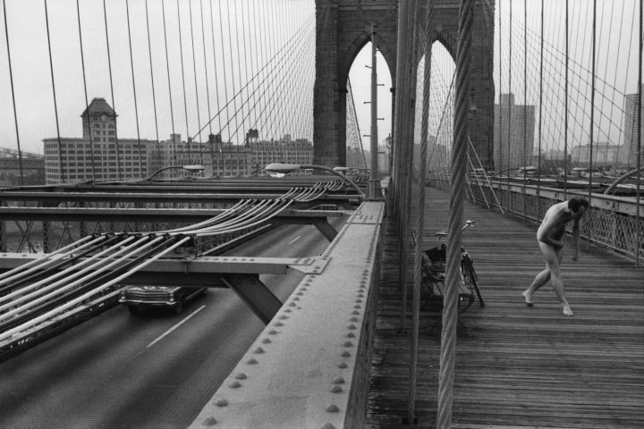 Black and white street photography by Richard Kalvar, nude man on Brooklyn Bridge