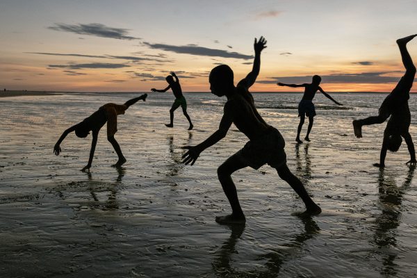 Color photograph by Steve McCurry, Madagascar, boys playing on beach, sunset, sillouhettes