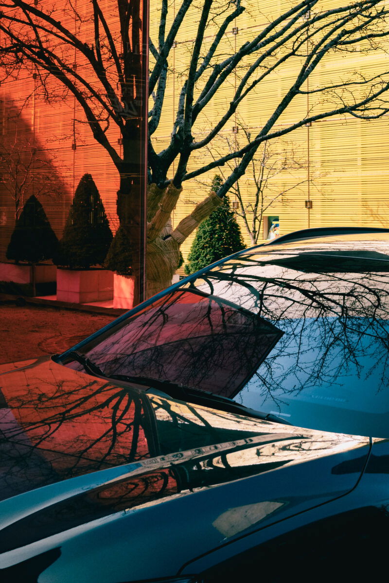 colorful picture of red and yellow buildings with car reflexion by Hansae Lee