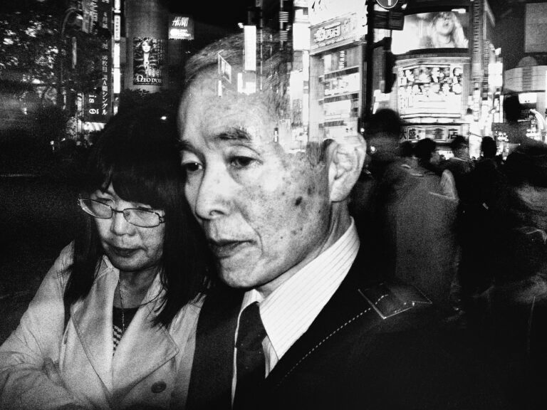 Black and white strete photography by Tatsuo Suzuki. close up portrait, city lights, Tokyo Japan