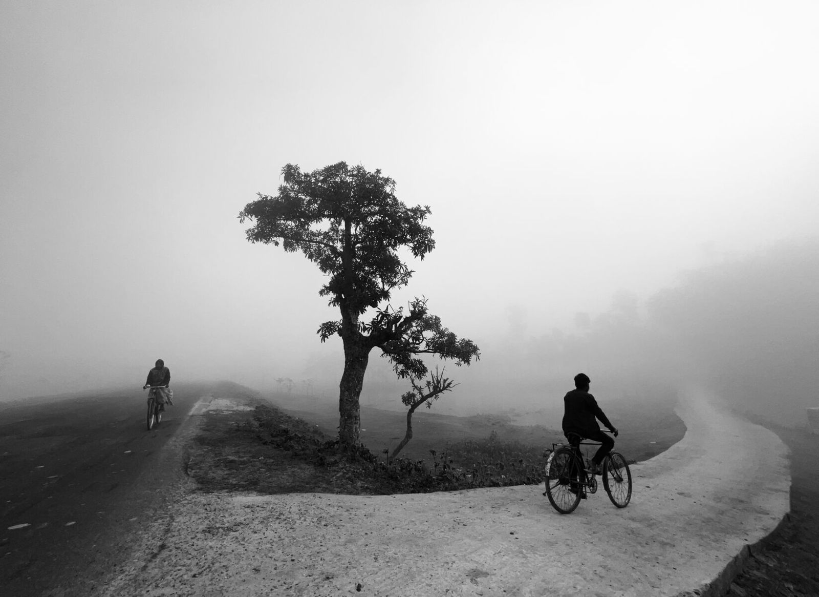 black and white landscape photo of men cycling in India by Dimpy Bhalotia