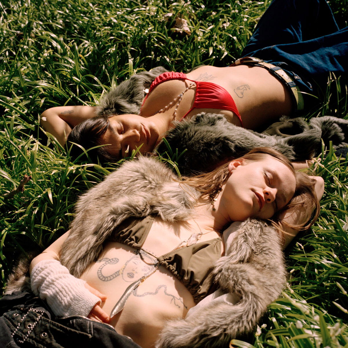 color fashion portrait of a two female models laying in grass by Lucia Jost