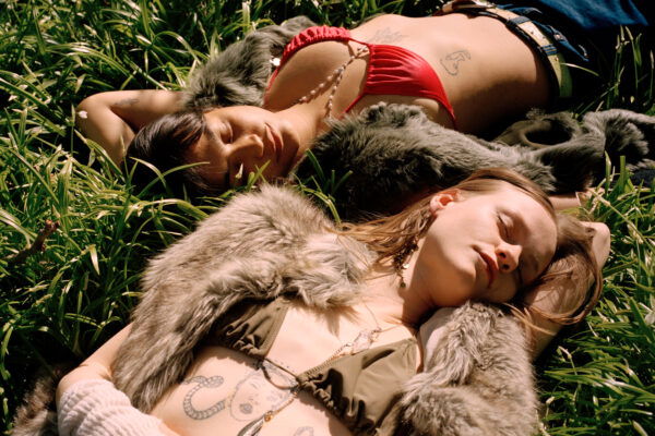 color fashion portrait of a two female models laying in grass by Lucia Jost