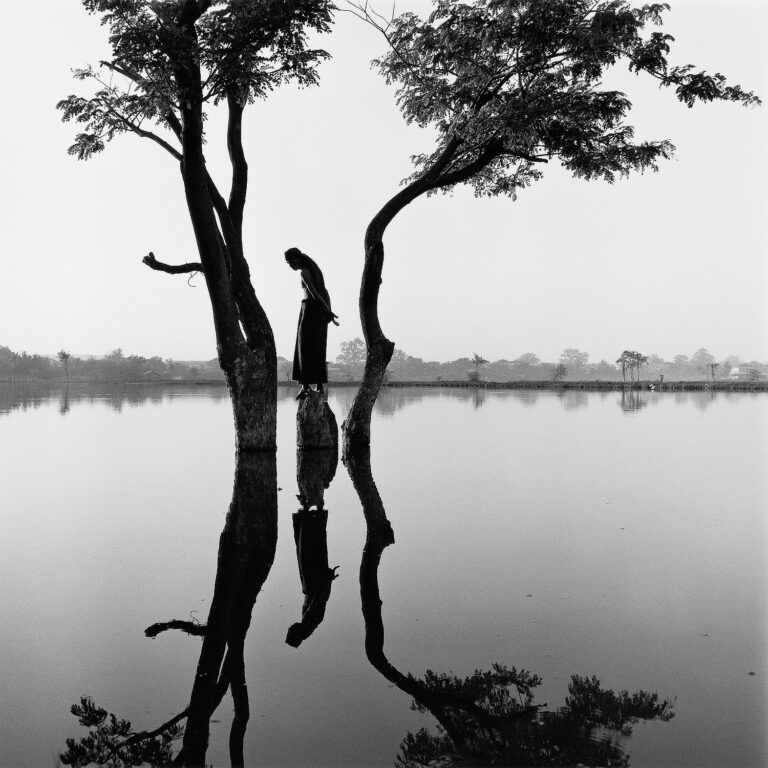 Black & white portrait photography by Monica Denevan. Man, two trees, lake, Burma, Myanmar