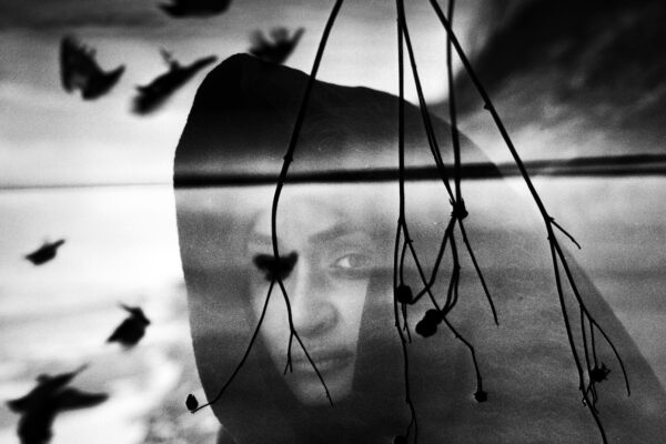 black and white double exposure photo of woman with sea and birds by Mindaugas Gabrenas