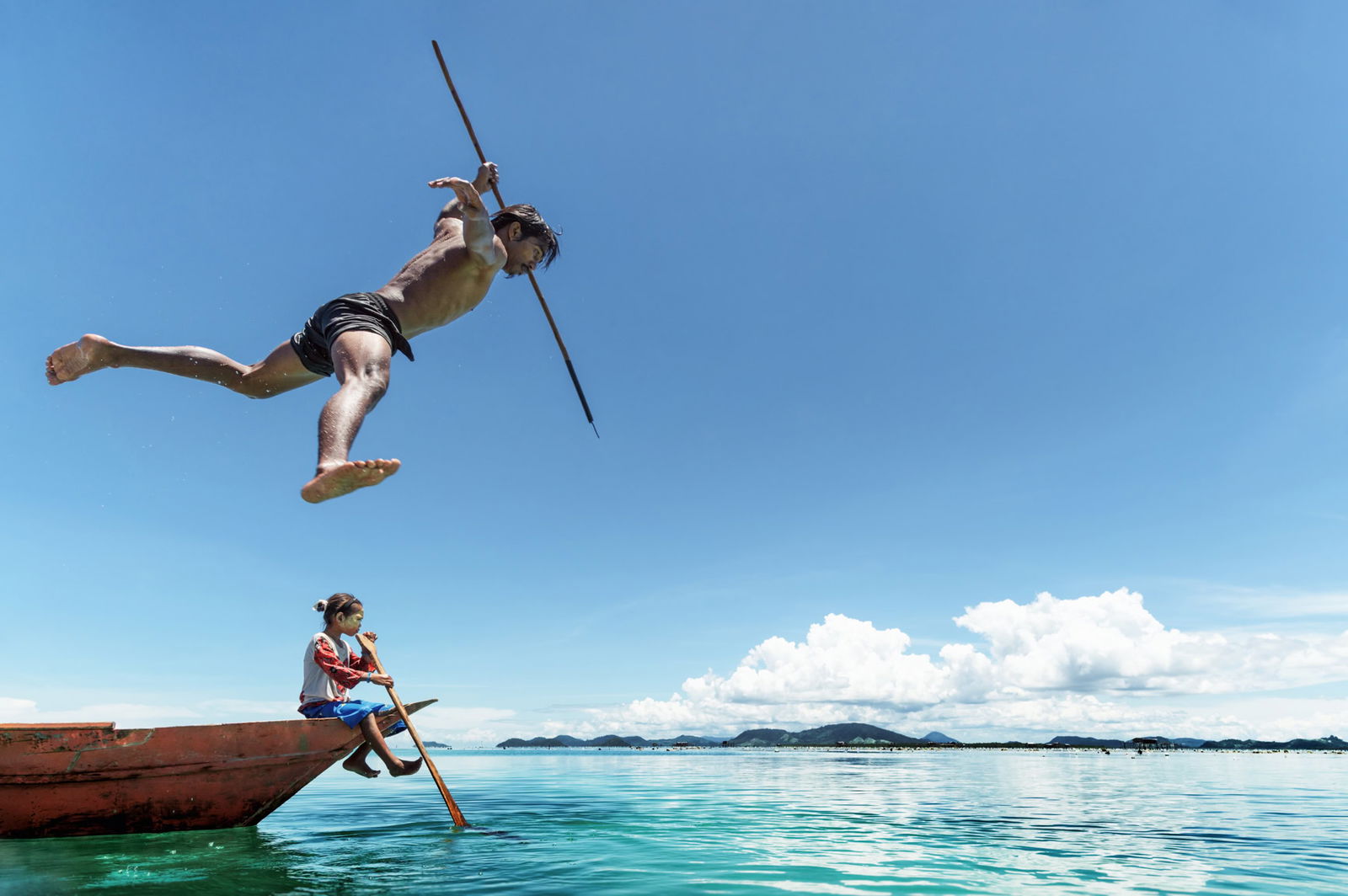 Documentary photography by Jacopo Della Valle. Photo of a man jumping off a boat with a spear