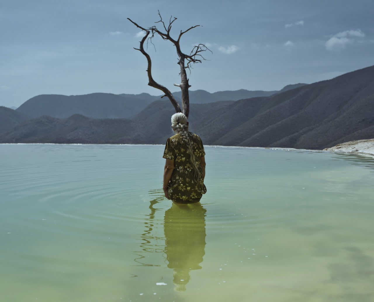 Photo of a woman in a lake looking out over mountains by Cristina De Middel