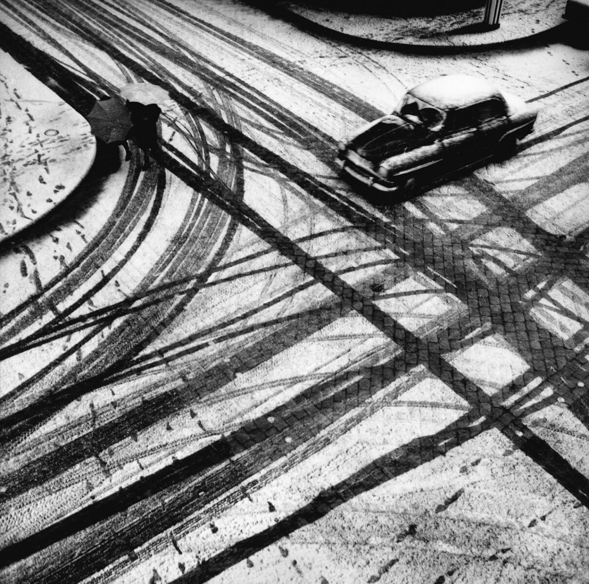 Black & white photo of a car driving through snow