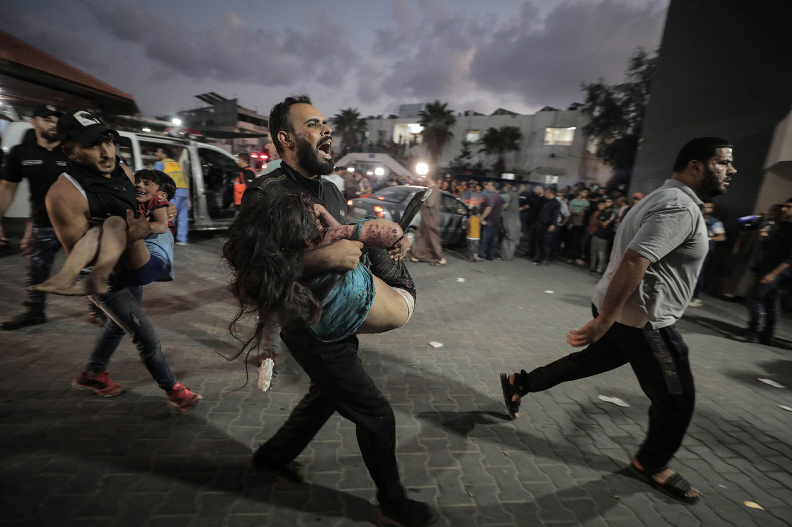 Photo of a man carrying a dying child after an Israeli airstrike in Gaza