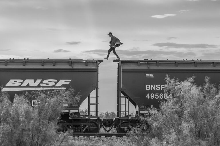 Black & white photo of a migrant on top of a freight train in Mexico