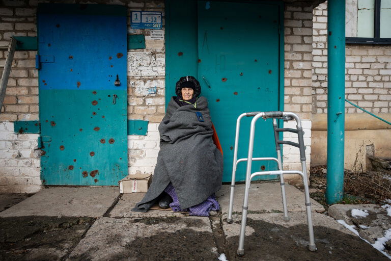 Portrait photo of an elderly woman outside her home damaged by shells in Siversk, Donbas, Ukraine