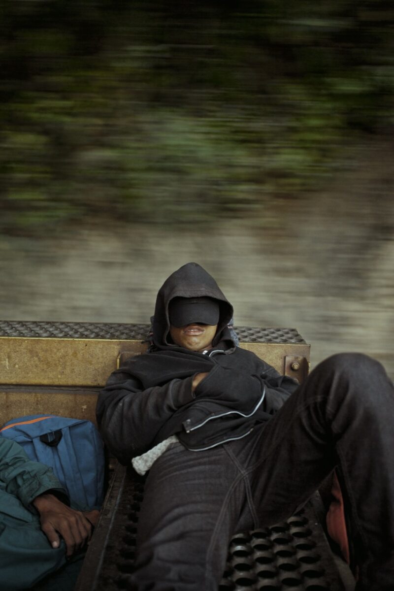 Photo of a man asleep on top of a train by Cristina de Middel