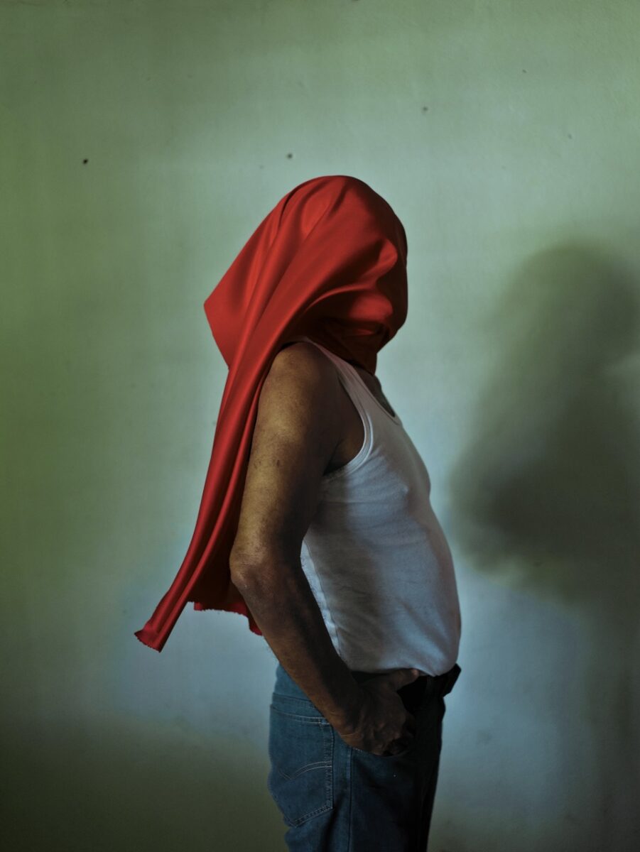 Photo of a man with a red cloth over his face by Cristina de Middel