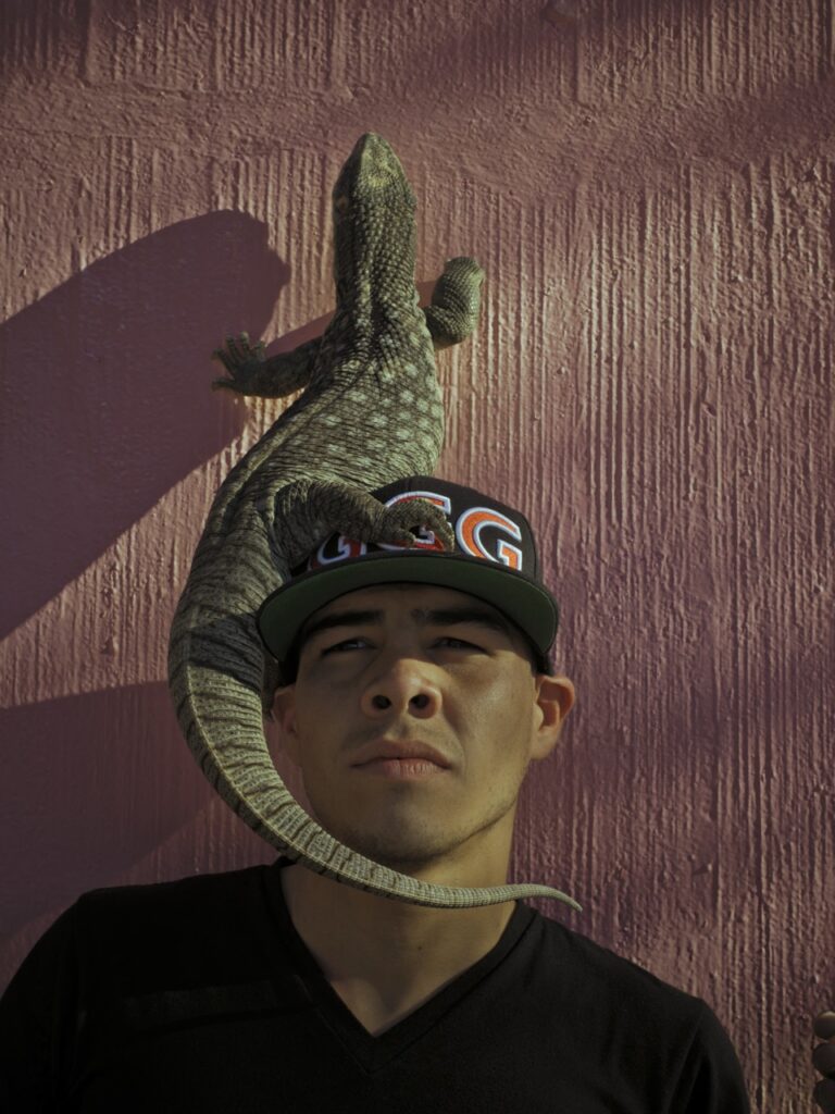 Portrait photography of a man with a lizard on his head by Cristina de Middel