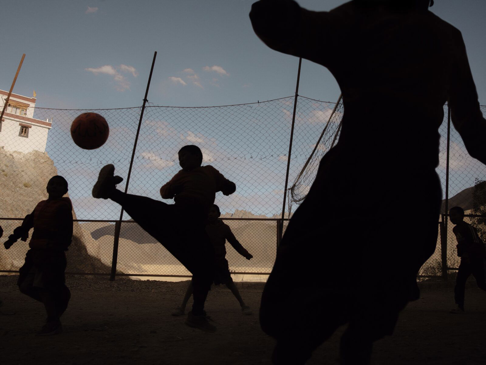 Travel photography by Pie Aerts. Silhouettes of people playing football in the mountains