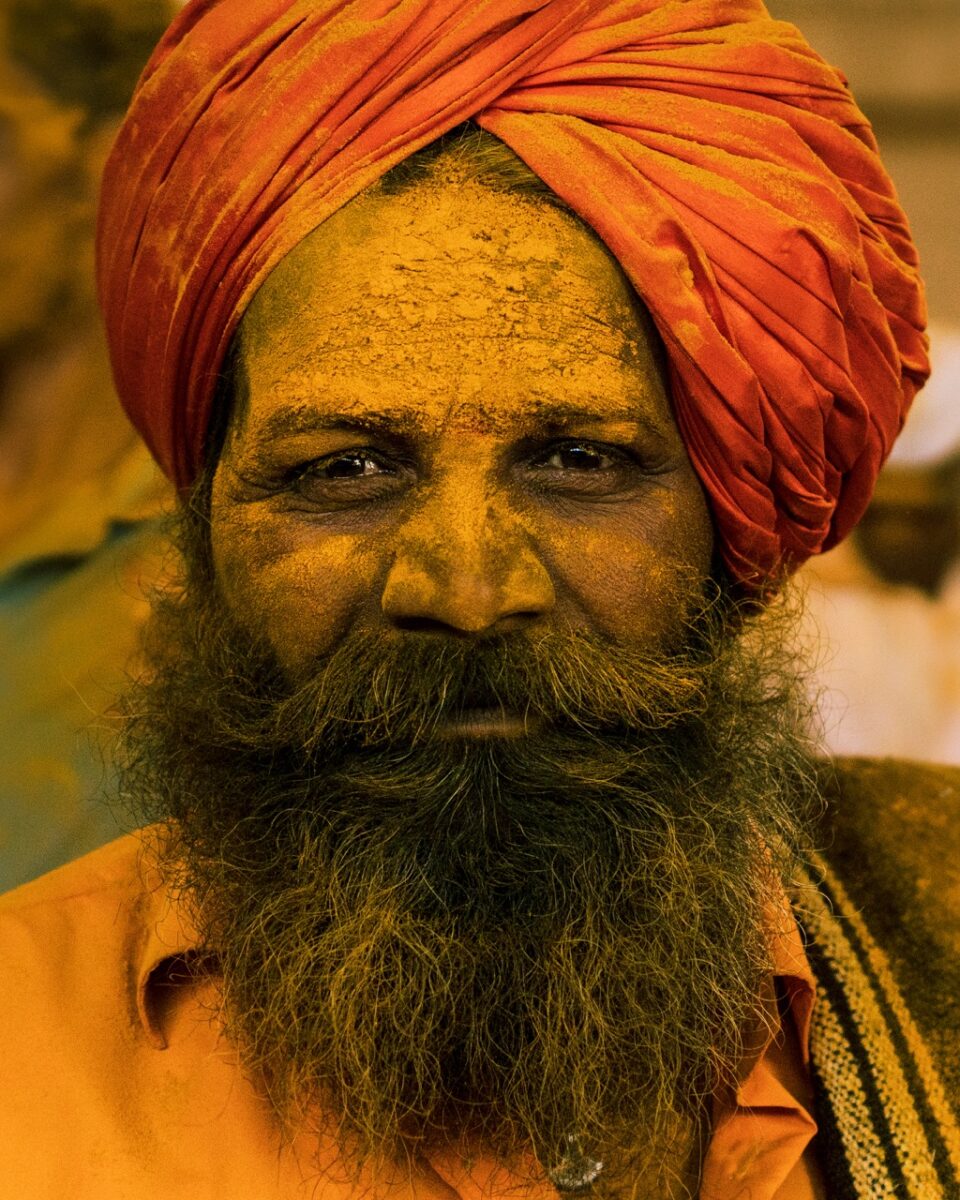 Color travel photography by Mahendra Bakle. Portrait of a man in a red turban with yellow paint on his face