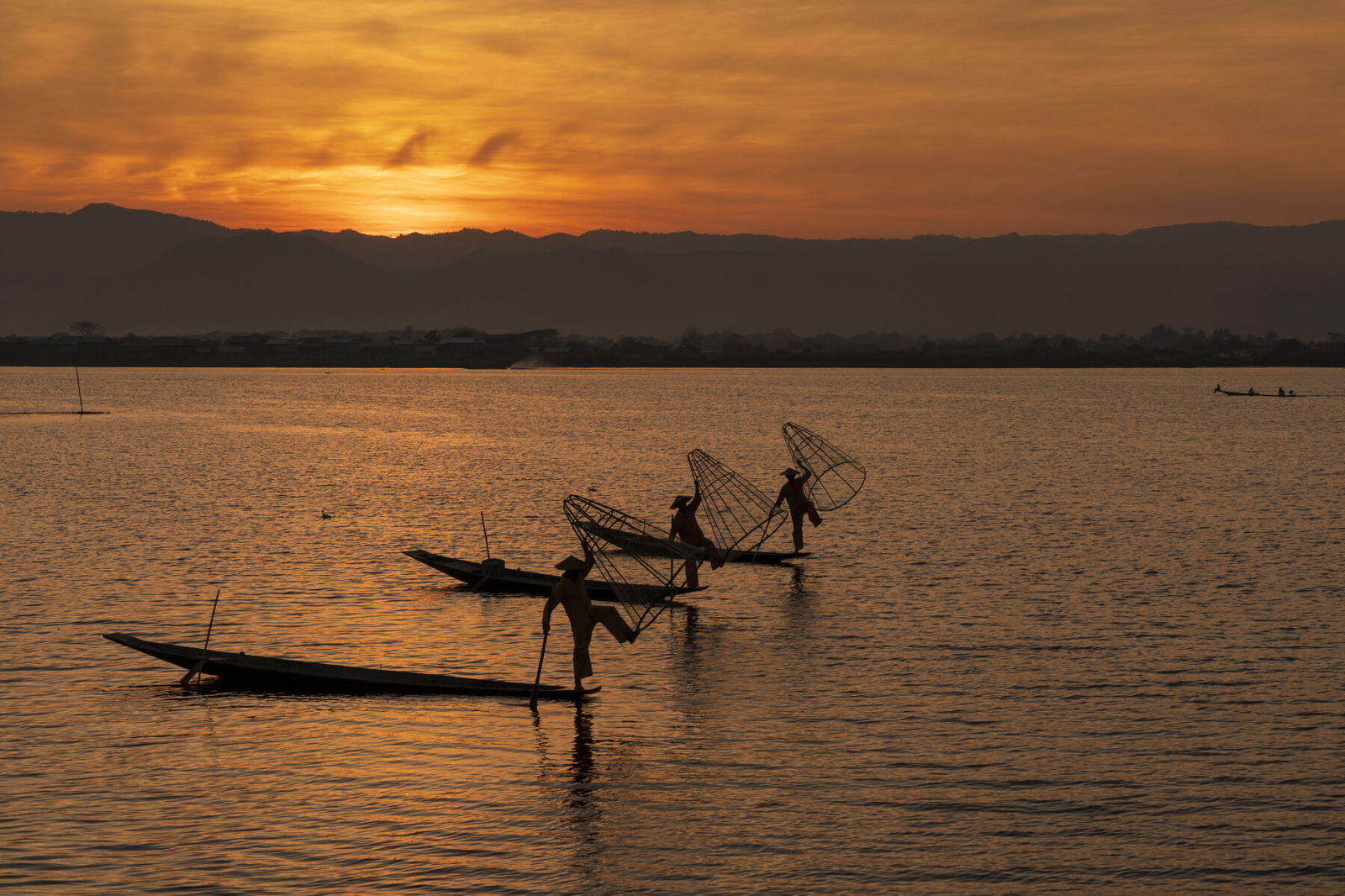 Color travel photography by Mahendra Bakle. Sunrise over a lake with people fishing in Myanmar