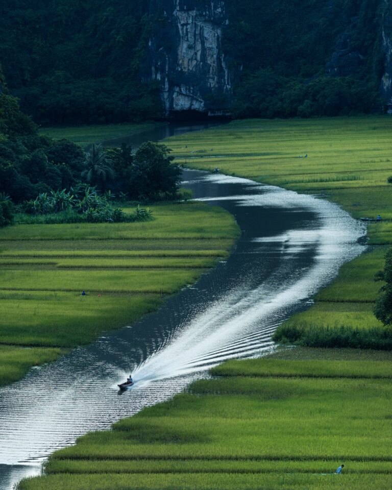 Color travel photography by Mahendra Bakle. A boat going down a river among rice fields