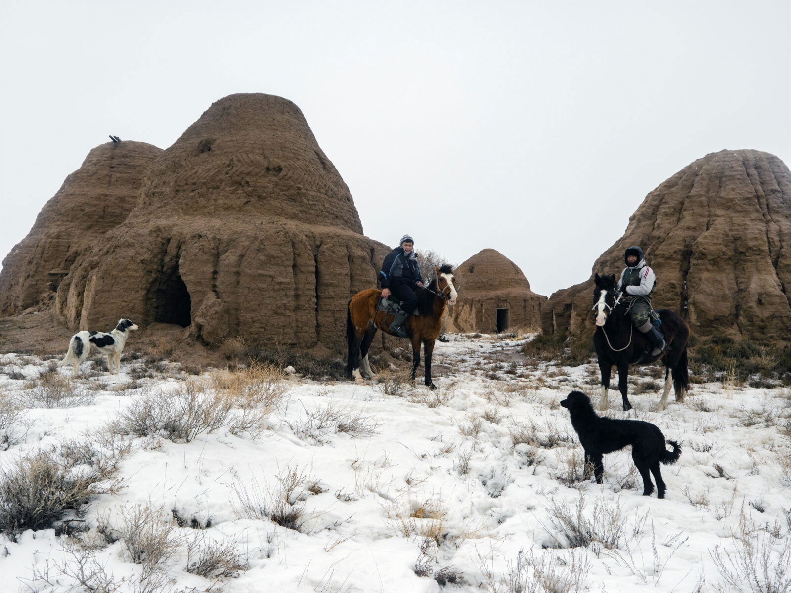 Documentary photography by Andrew McConnell.. Men on horses, in front of nomadic burial tombs, Soyuz landing zone, Kazakhstan 2018.