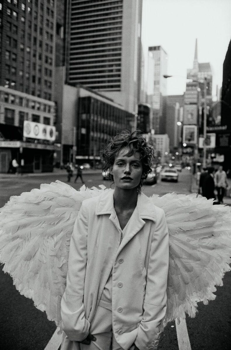 Black and white portrait of a woman with a white outfit and wings in NYC, by Peter Lindbergh