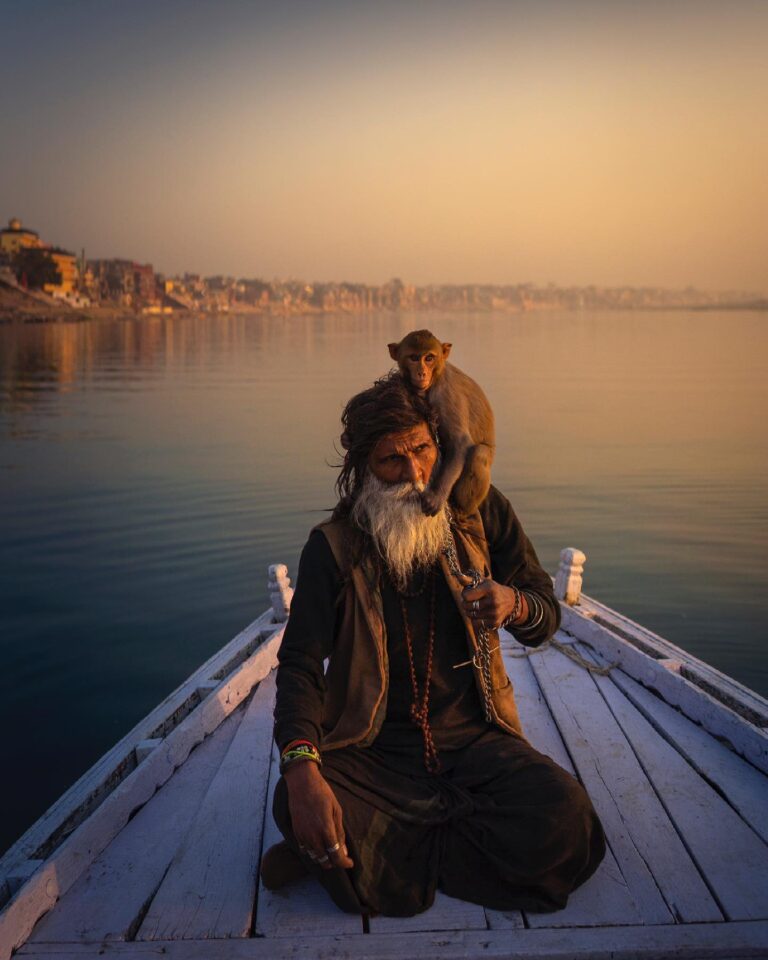 Color travel photography by Mahendra Bakle. Portrait of a man and monkey on boat n Varanasi.