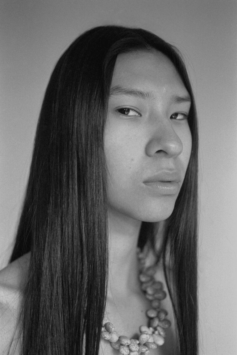 Black & white portrait photography of a young man with long straight hair by Marisol Mendez