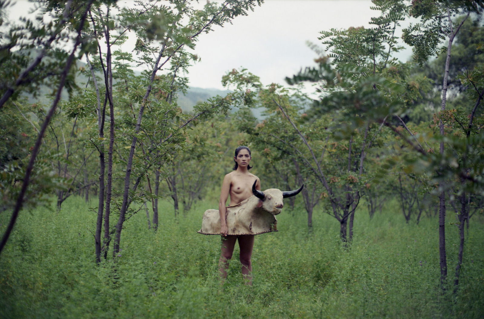 Portrait photo of a naked woman with a bull outfit around her waist by Marisol Mendez