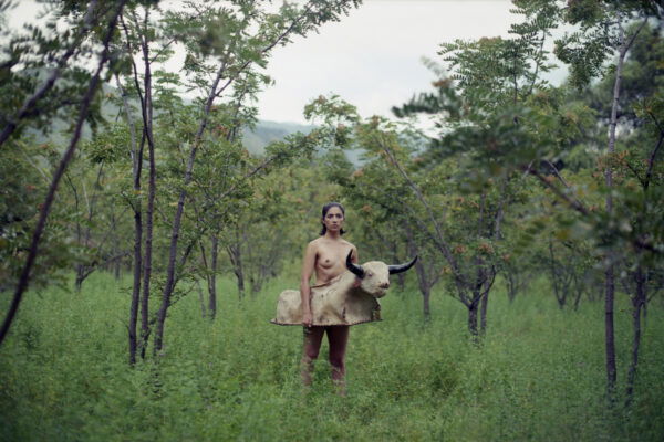 Portrait photo of a naked woman with a bull outfit around her waist by Marisol Mendez