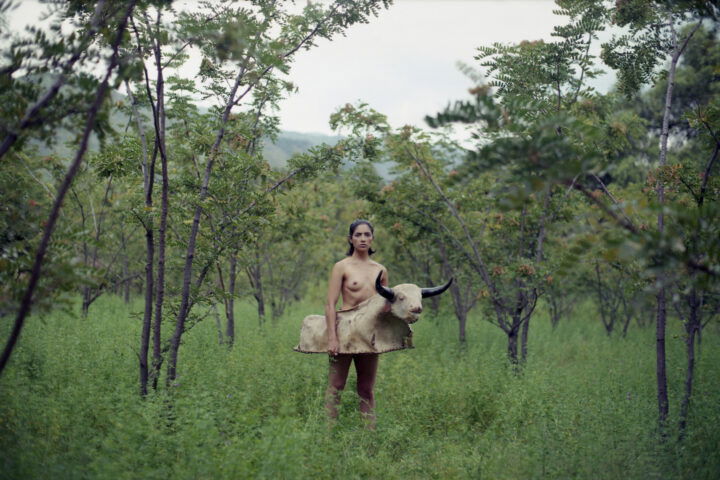 Portrait photo of a naked woman with a bull outfit around her waist by Marisol Mendez