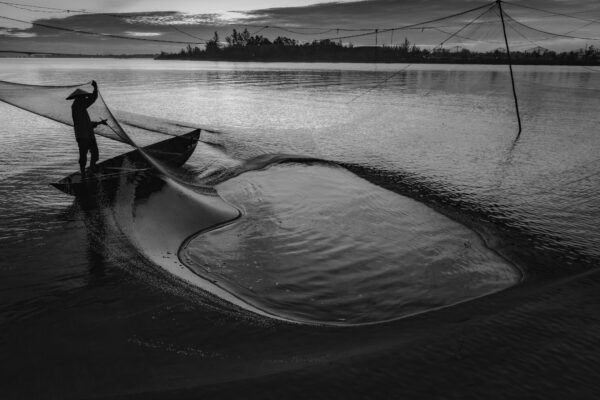 black and white landscape travel photo of fisherman in Hoi An, Vietnam by Chan Kim