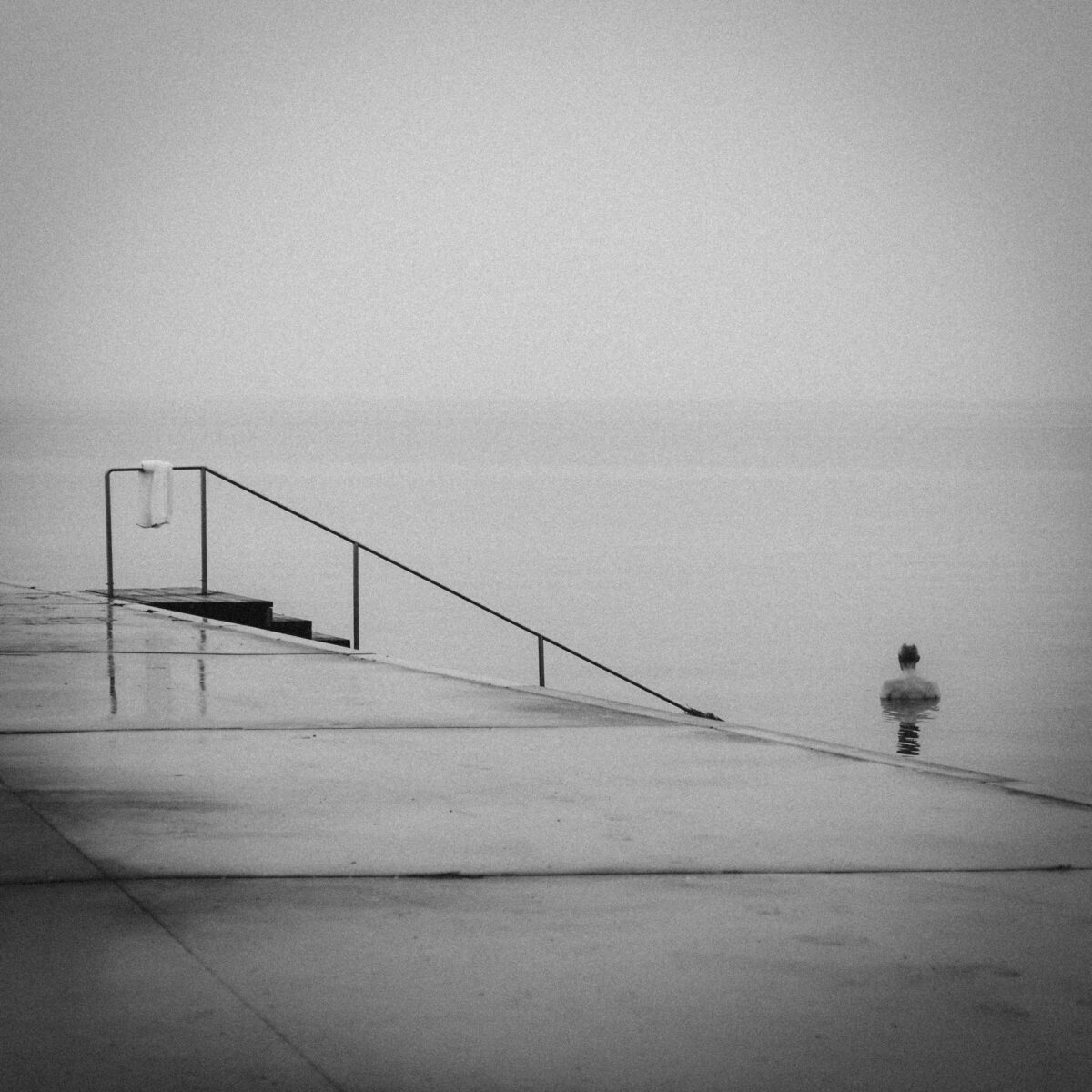 black and white photo of man swimming in Bellevue Strand, Klampenborg, Denmark by Mette Ovgaard