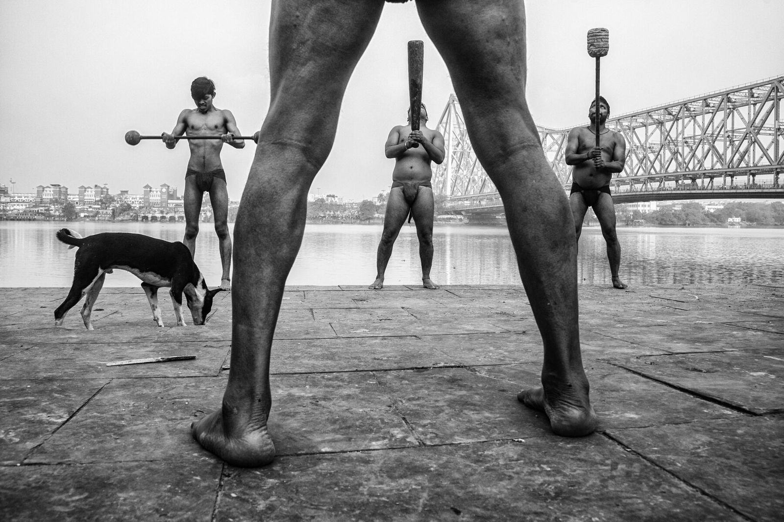 black and white street photo of men practising kushti in India by Sanghamitra Sarkar